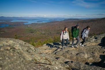 Three young people on rocky mountaintop with lake in background